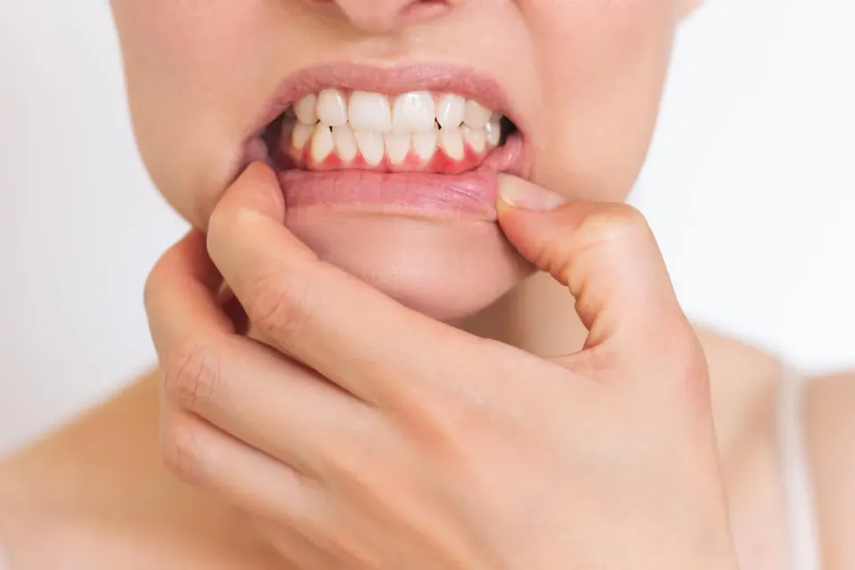 Patient wincing after drinking a cold beverage, indicating tooth sensitivity symptoms
